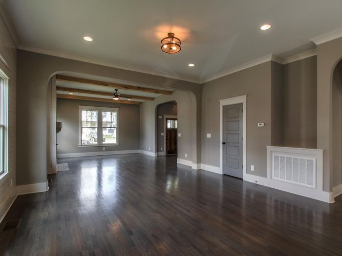 A hallway with arched openings and wainscoting, the floor running through each opening without a threshold strip
