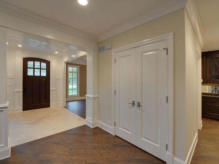 A front entry hall with double doors and panelled trim, floored through to the rooms beyond