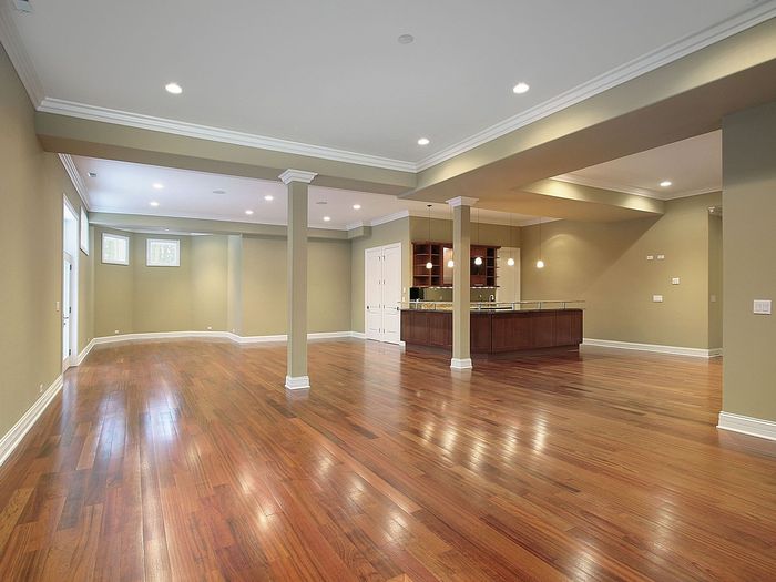 An open lower level with support columns, floored in a warm oak tone from wall to wall
