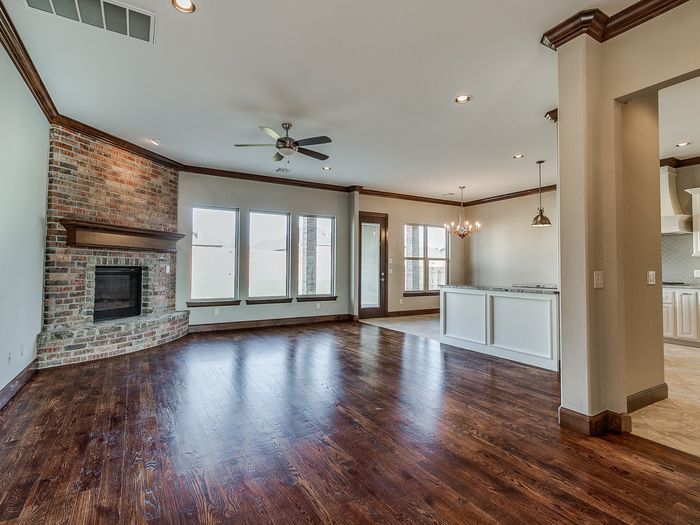 An open plan living and kitchen area in a dark floor, running unbroken past a brick fireplace