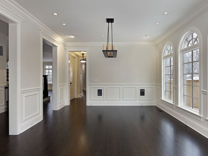 A room with full wainscoting and arched windows, the floor finished up to the trim on every wall
